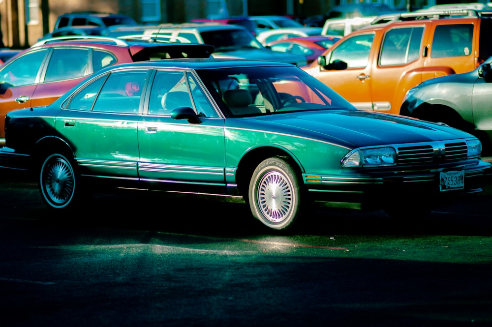 green sedan parked on parking lot during daytime