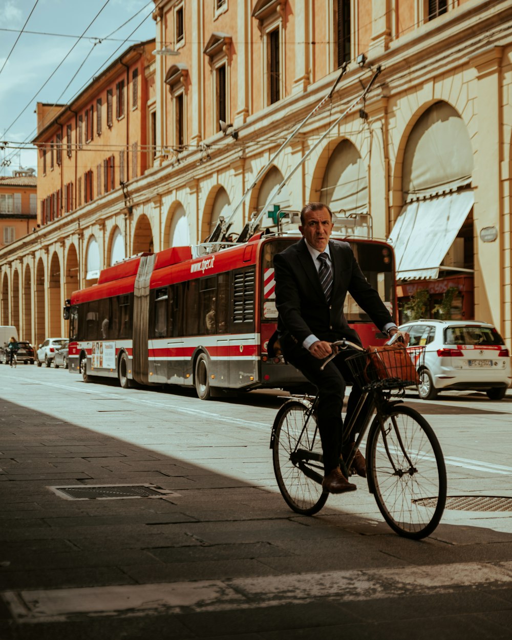 man in black suit riding bicycle on street during daytime