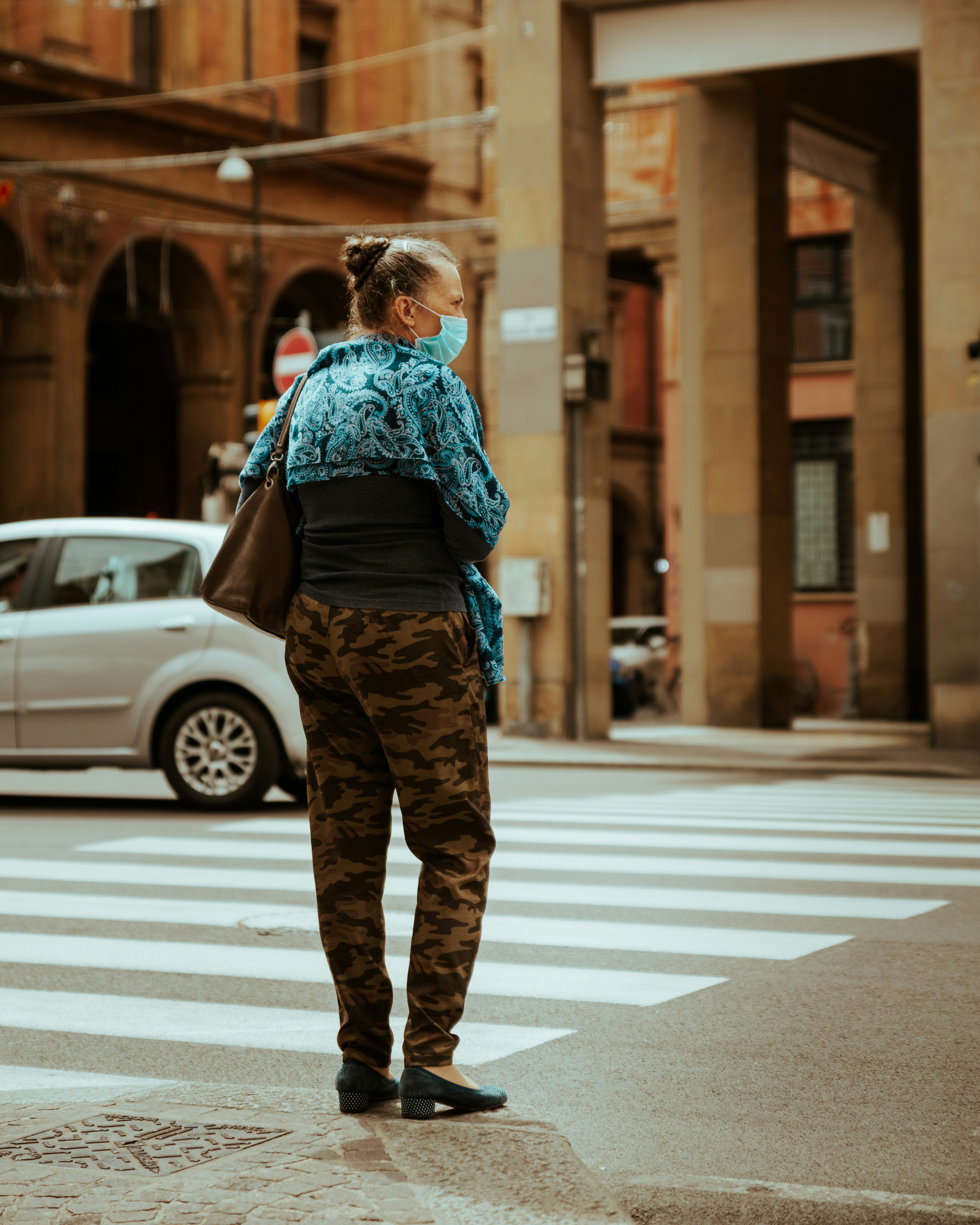 man in blue shirt and brown pants standing on pedestrian lane during daytime
