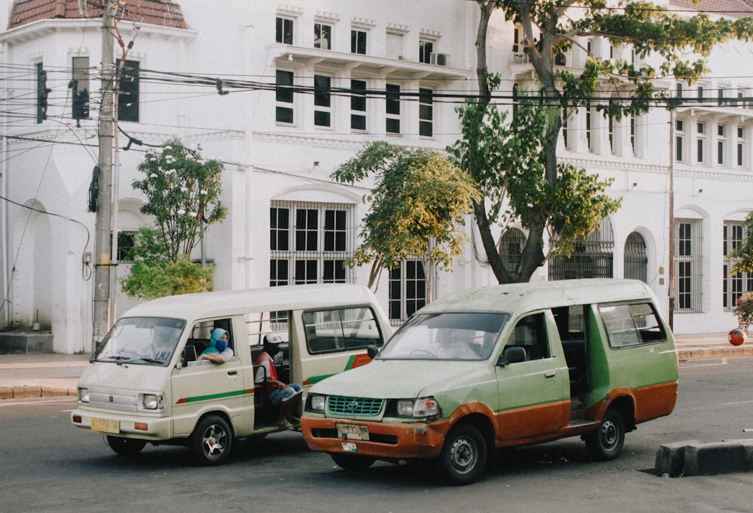 white and green van parked beside white concrete building during daytime
