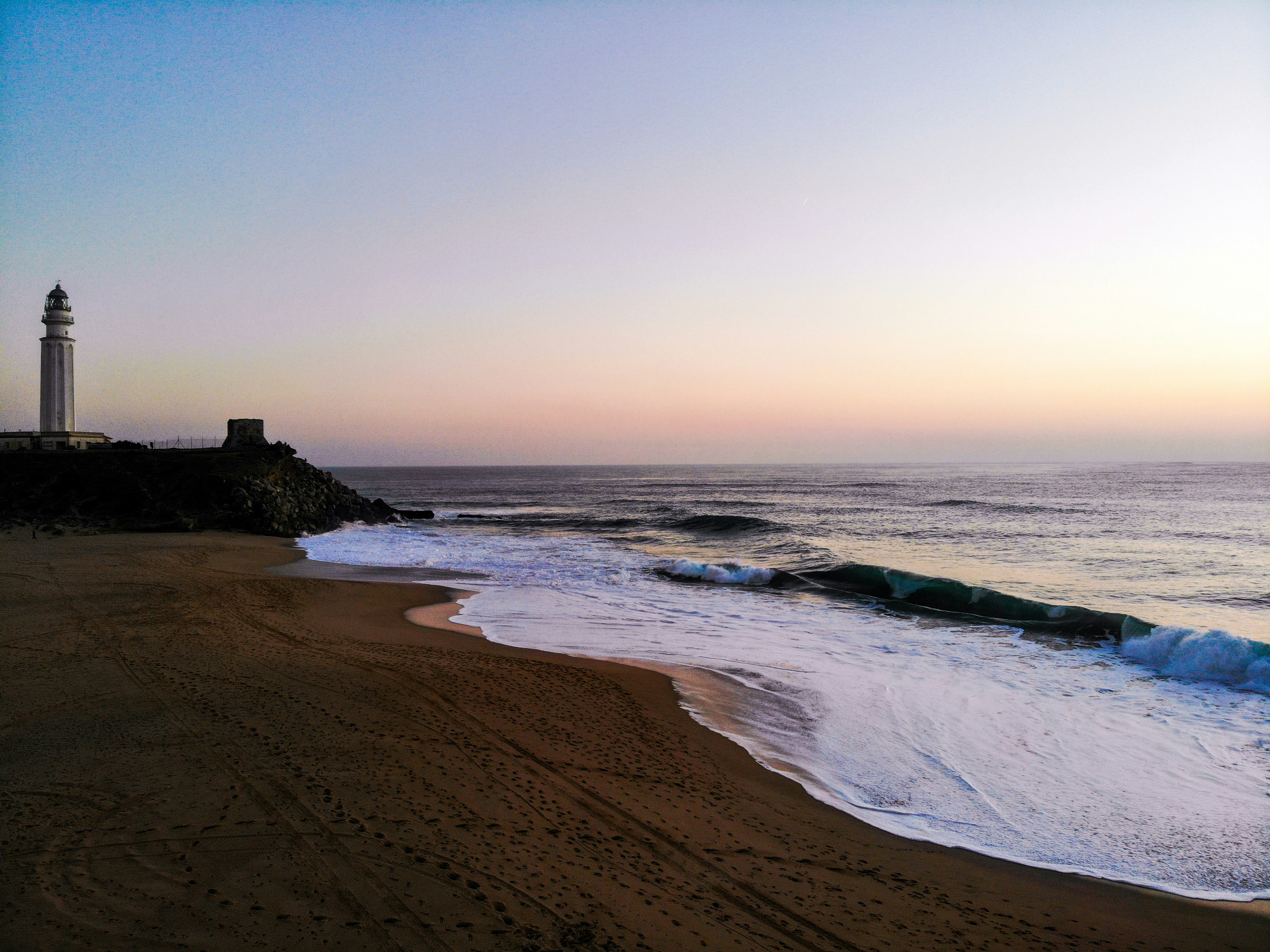 a beach with a light house in the distance