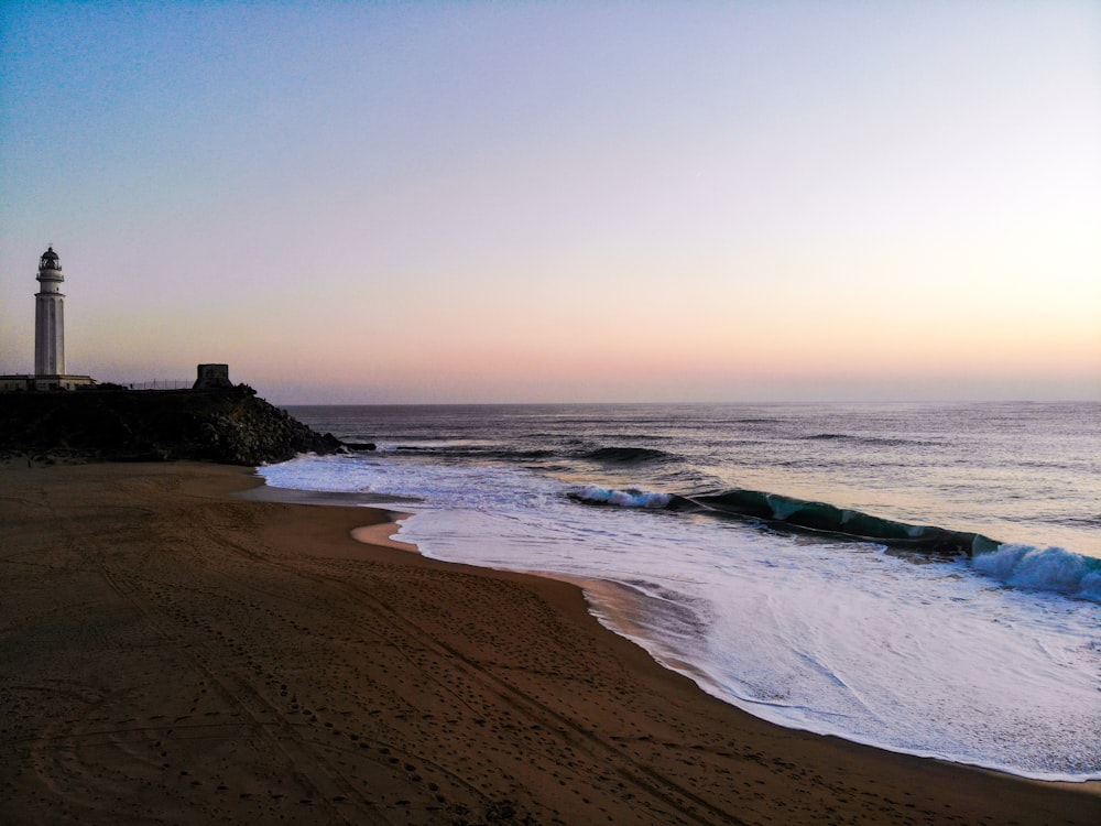 a beach with a light house in the distance