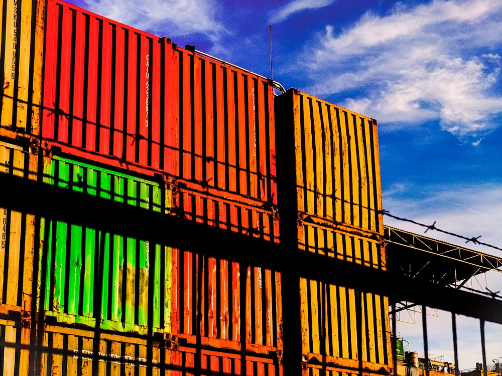 orange and blue steel containers under blue and white sunny cloudy sky during daytime