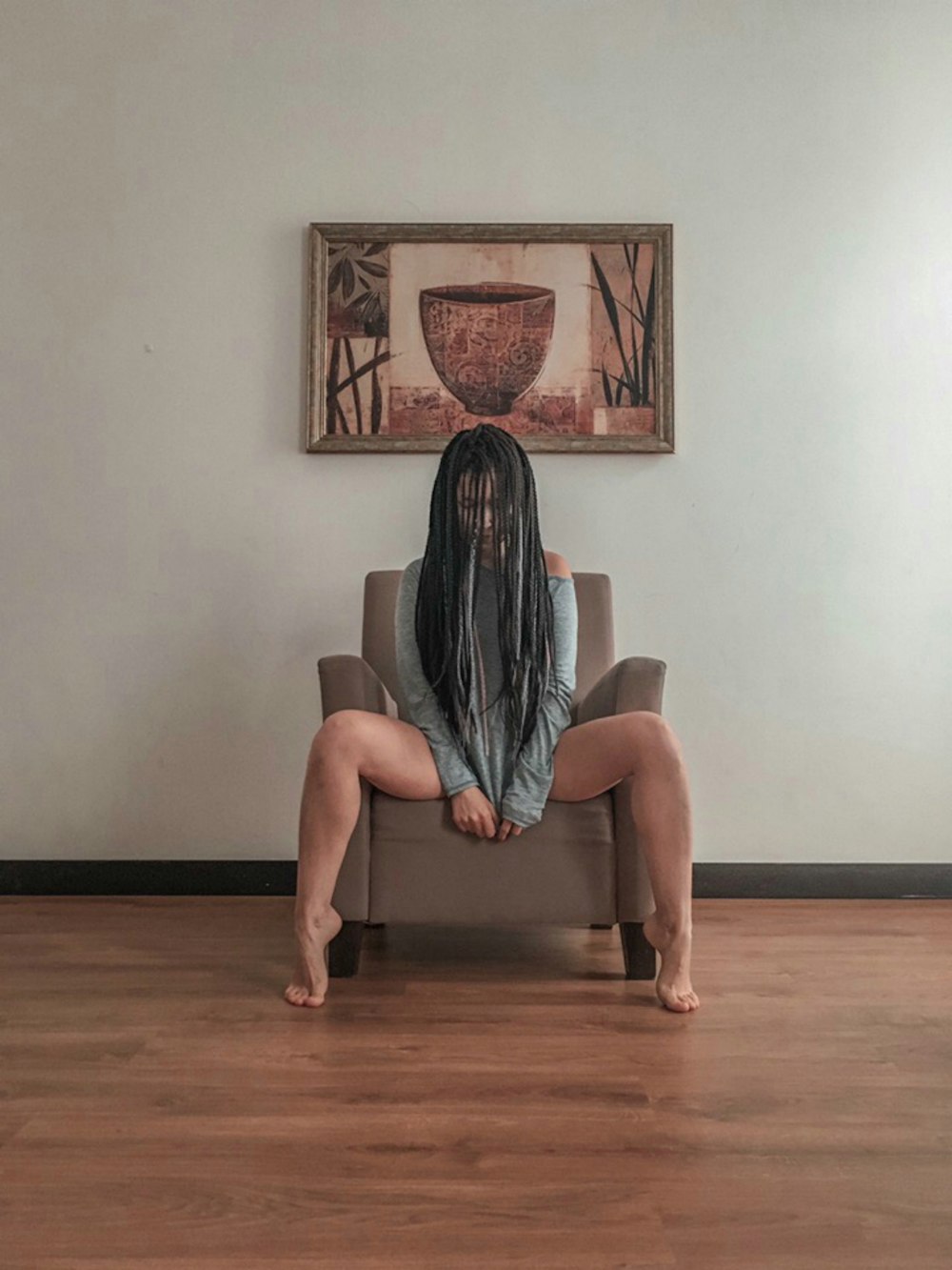 woman in gray dress sitting on brown sofa chair