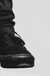 Close-up of a sleek black leather Velaro sneaker with gold accents on a white background