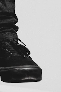 Close-up of a sleek black leather Velaro sneaker with gold accents on a white background