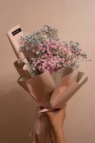 A delicate hand-tied bouquet with soft pastel flowers in minimalist wrapping.
