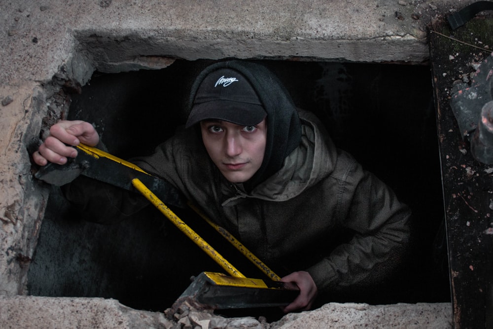 man in black hoodie and black cap holding yellow bar