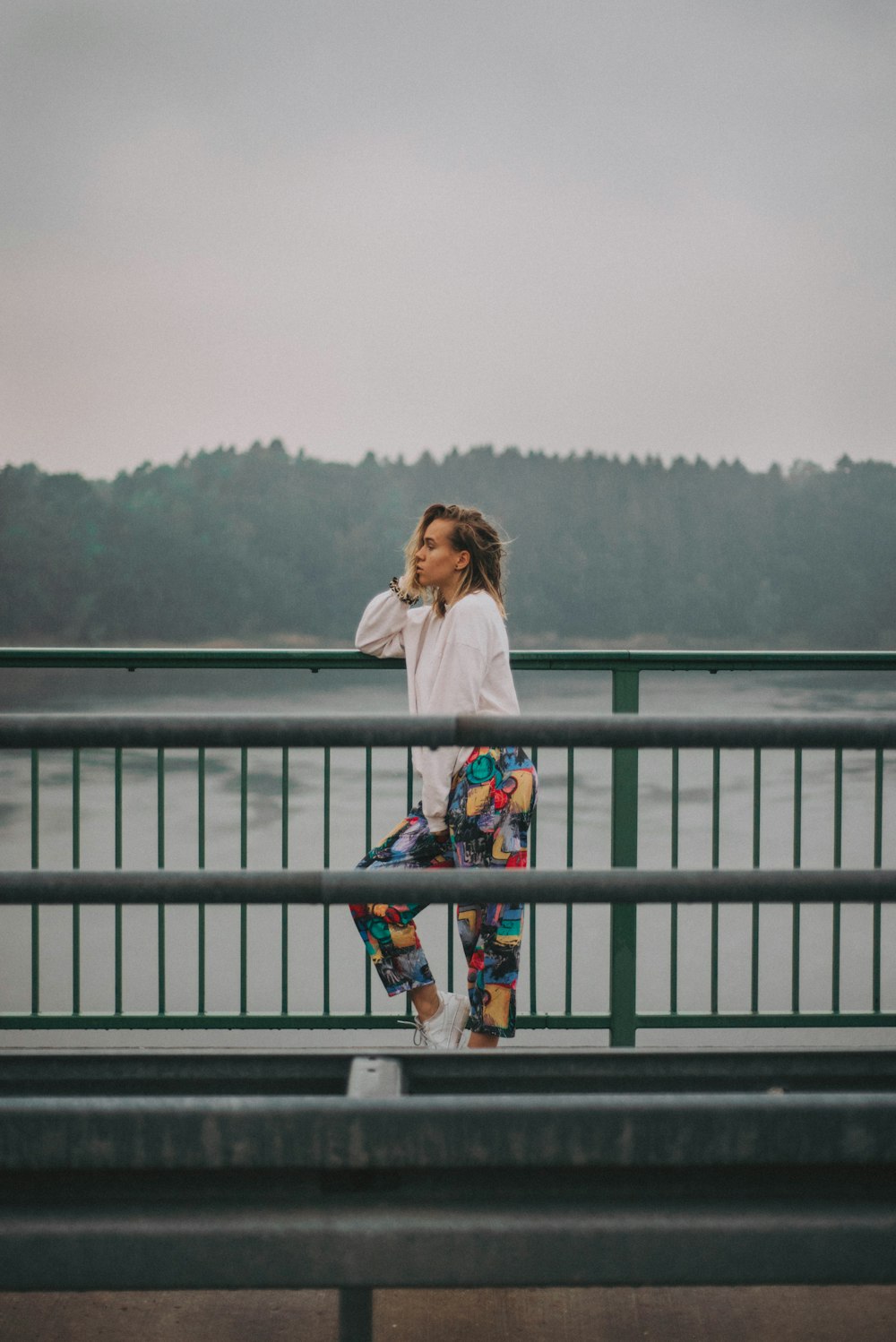 woman in white long sleeve shirt standing on gray wooden railings during daytime