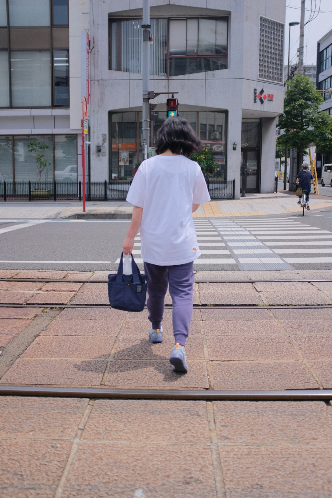 woman in white t-shirt and black pants walking on sidewalk during daytime