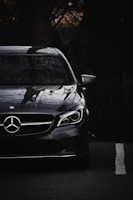 A sleek black Mercedes-Benz S-Class parked against a dark, elegant urban backdrop with subtle orange highlights.