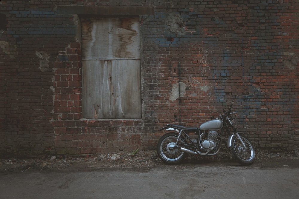 black motorcycle parked beside brown brick wall