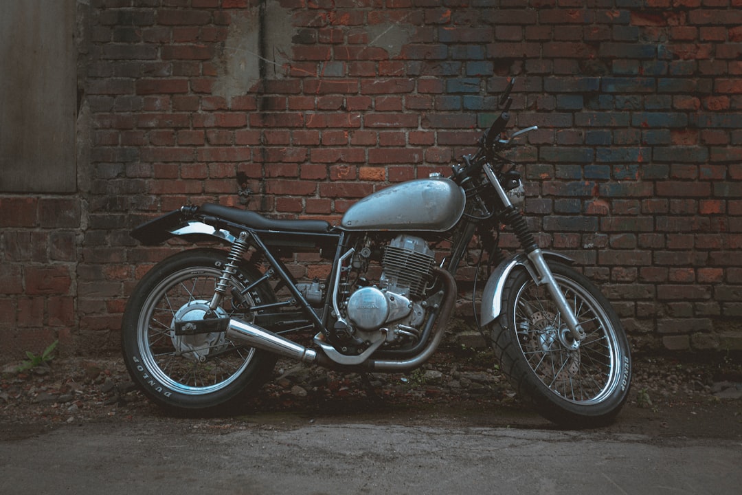 black standard motorcycle parked beside brown brick wall