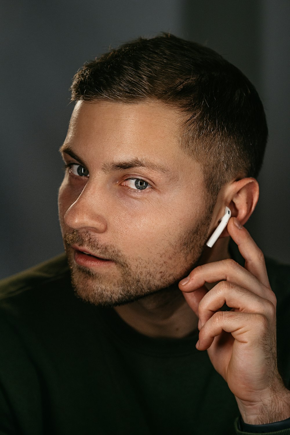 man in black crew neck shirt holding white smartphone