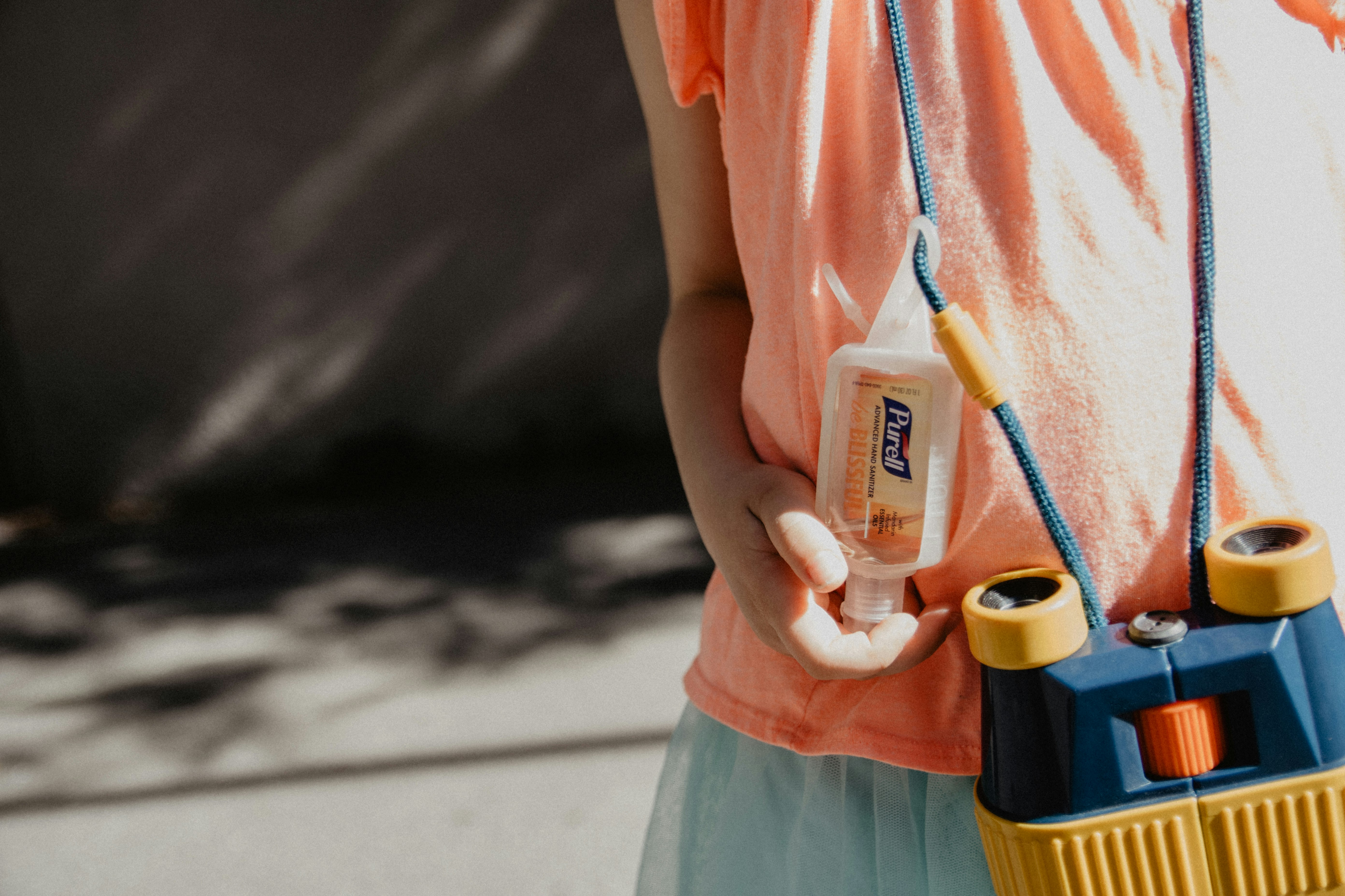 woman in pink shirt holding blue and yellow plastic bottle