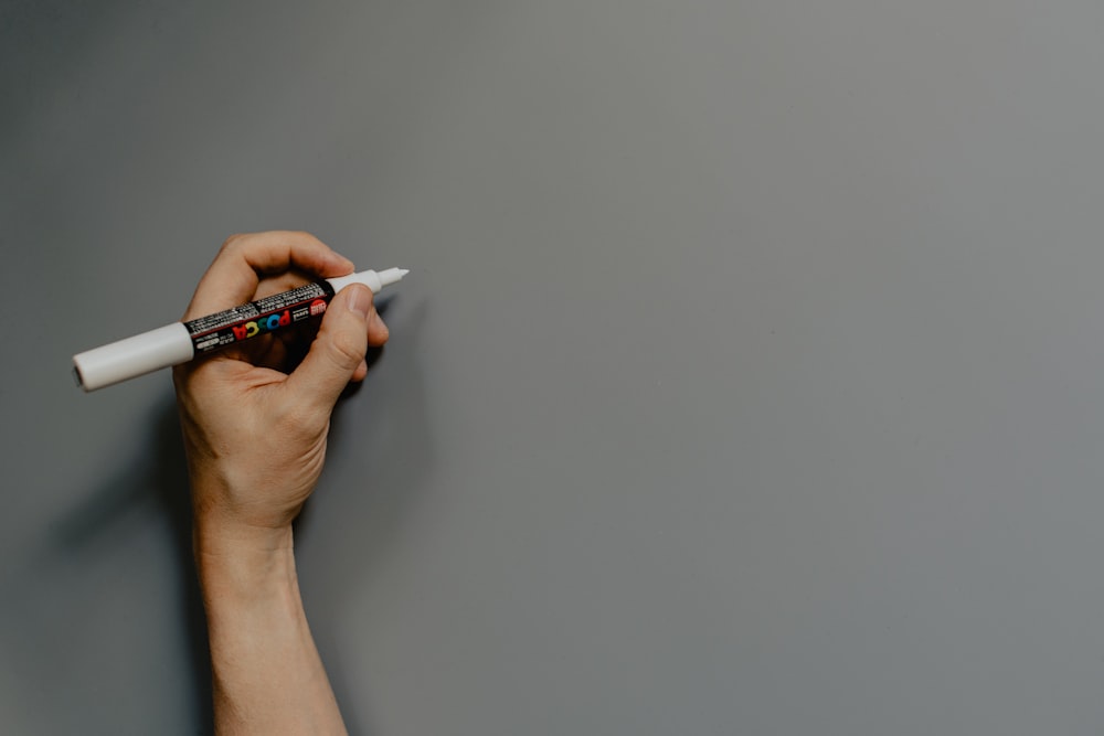 persona sosteniendo un bolígrafo blanco y negro