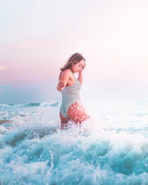woman in white and black polka dot bikini standing on sea waves during daytime