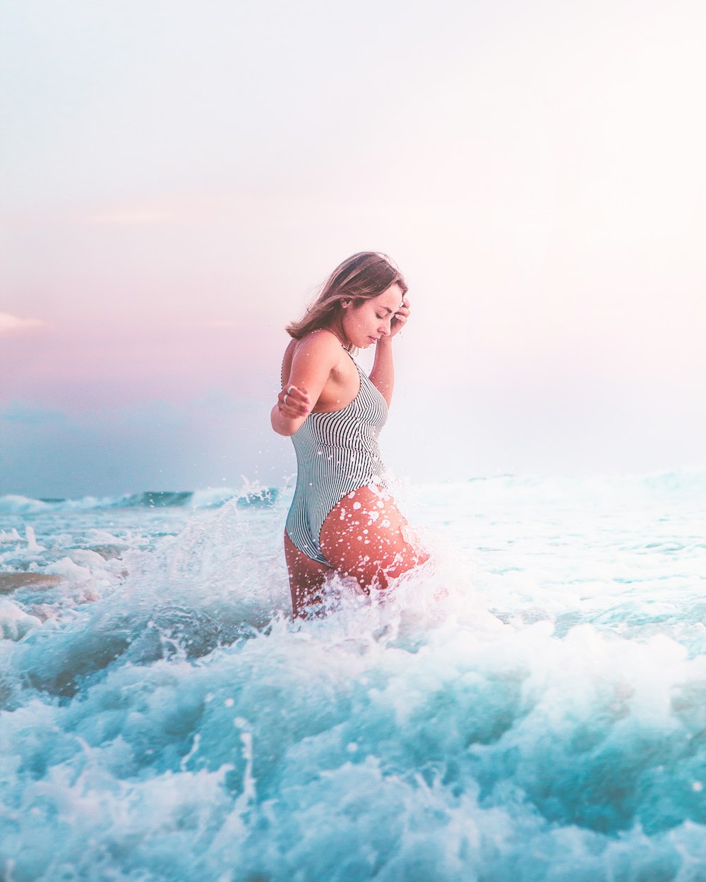 donna in bikini a pois bianco e nero in piedi sulle onde del mare durante il giorno