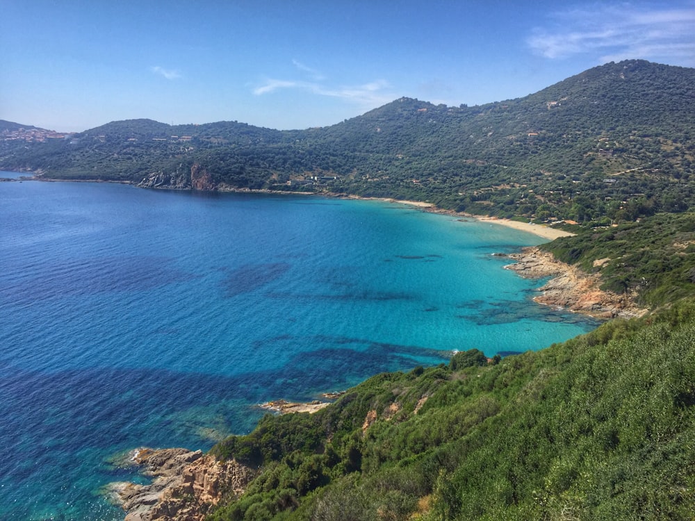 green mountain beside blue sea under blue sky during daytime