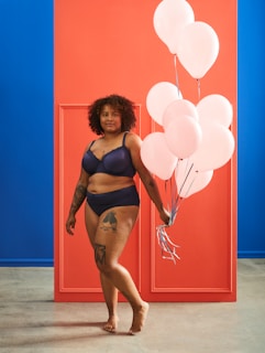 woman in black bikini standing beside red wall