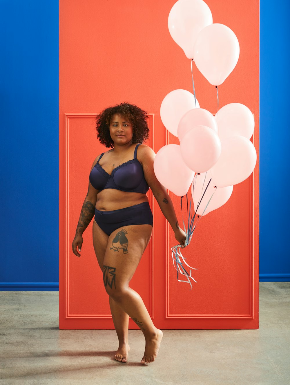 woman in black bikini standing beside red wall