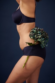 woman in black bikini holding bouquet of flowers