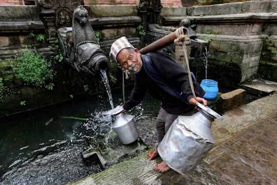 man in black jacket holding gray metal bucket in Kathmandu Nepal