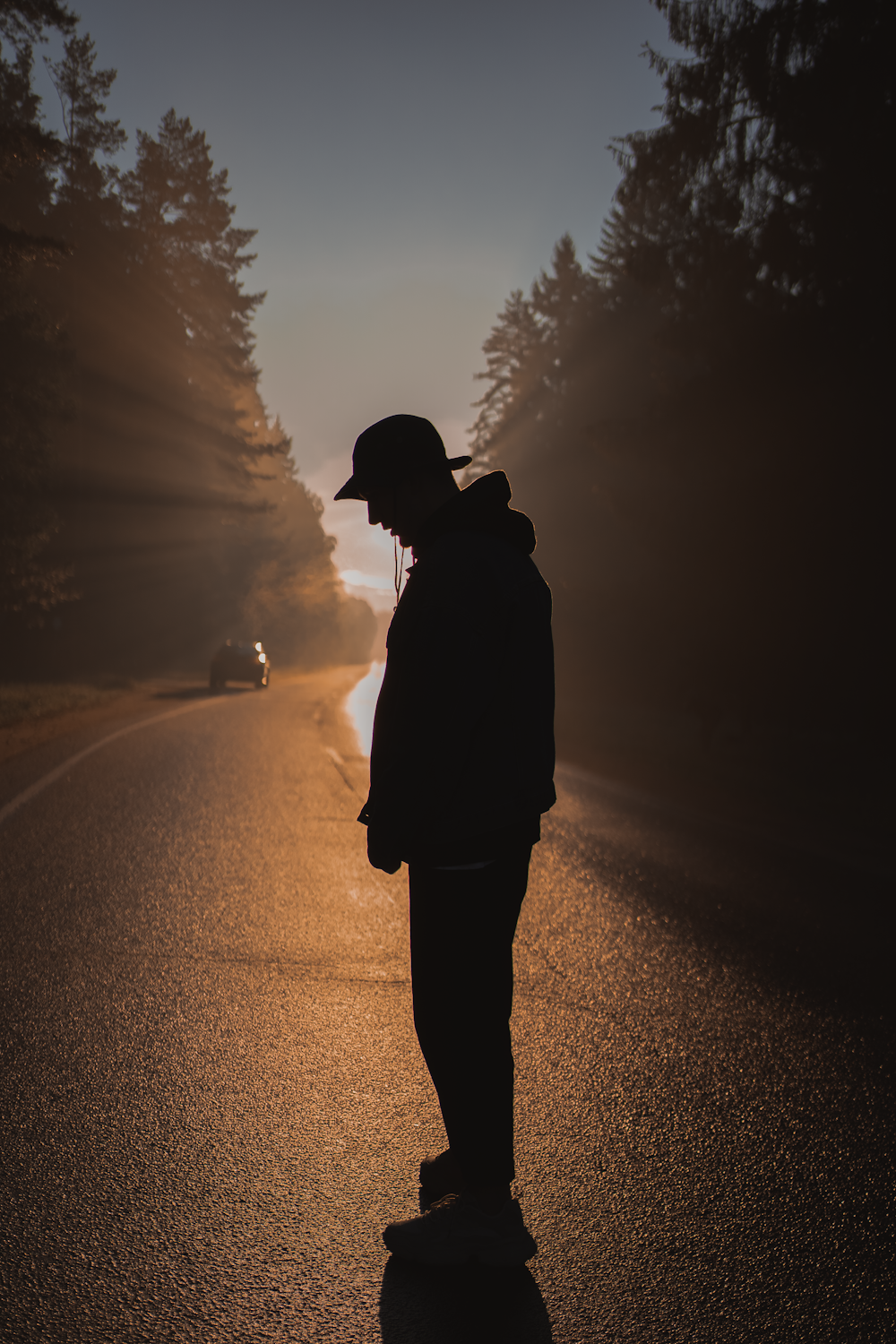 silhouette of man standing on road during sunset