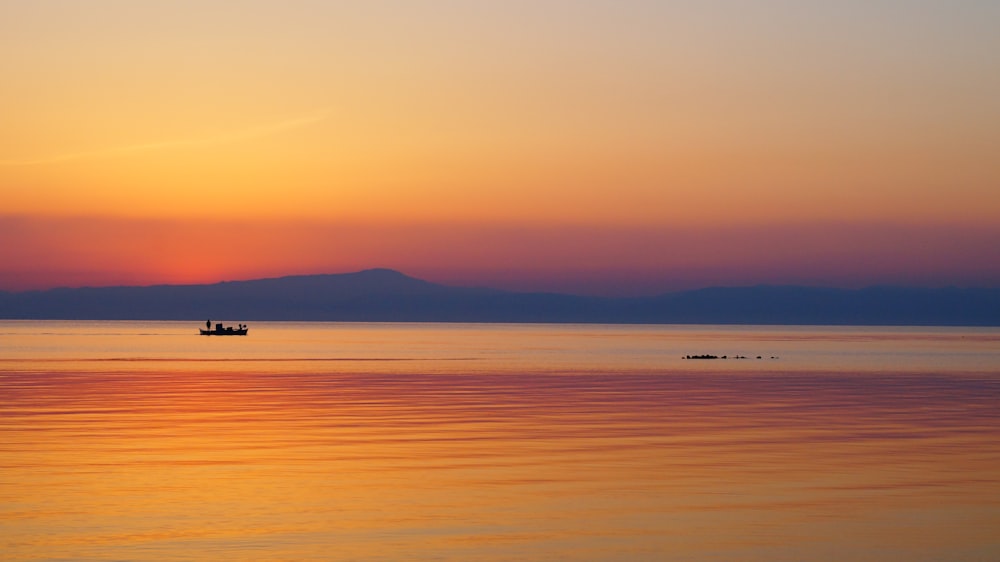 silhouette of boat on sea during sunset