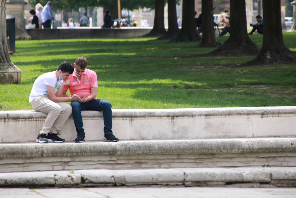 man and woman sitting on concrete bench during daytime