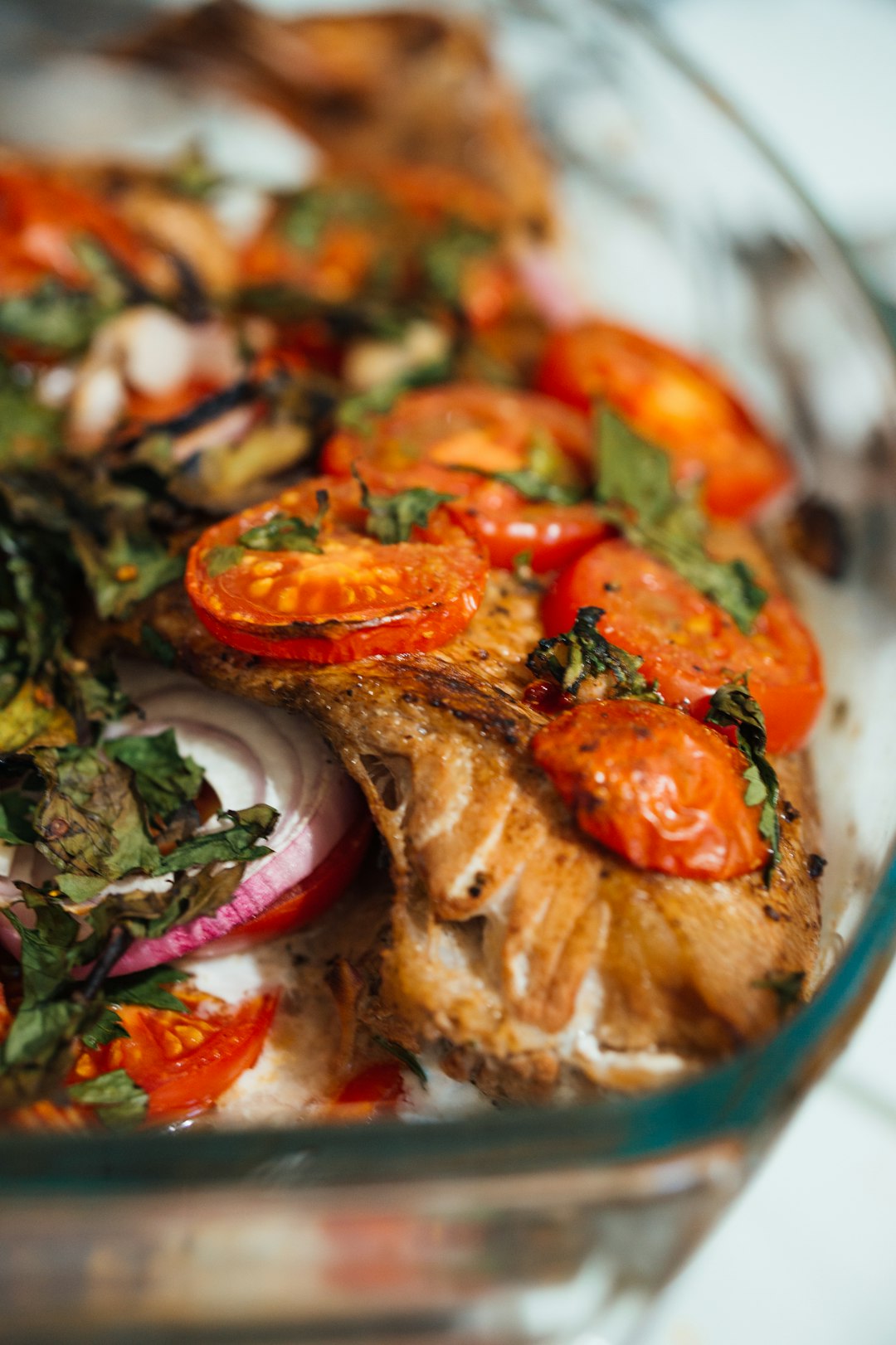 cooked food with sliced tomatoes and green leaves on blue ceramic bowl