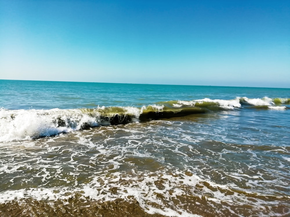 ocean waves crashing on shore during daytime