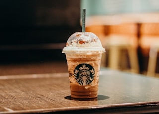 white and brown starbucks coffee cup on brown wooden table