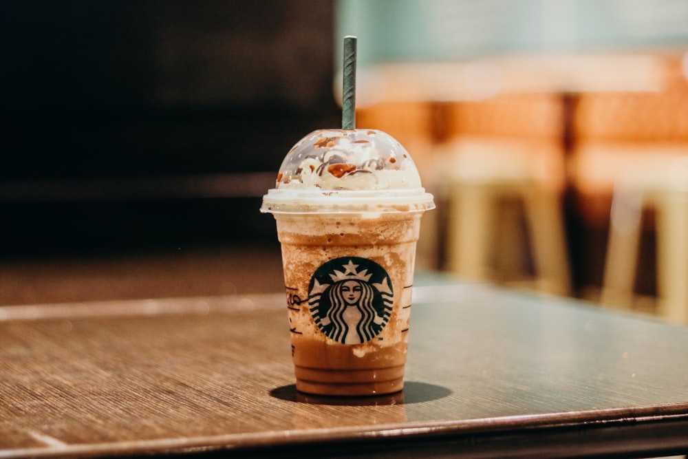 Tazza da caffè Starbucks bianca e marrone su tavolo di legno marrone