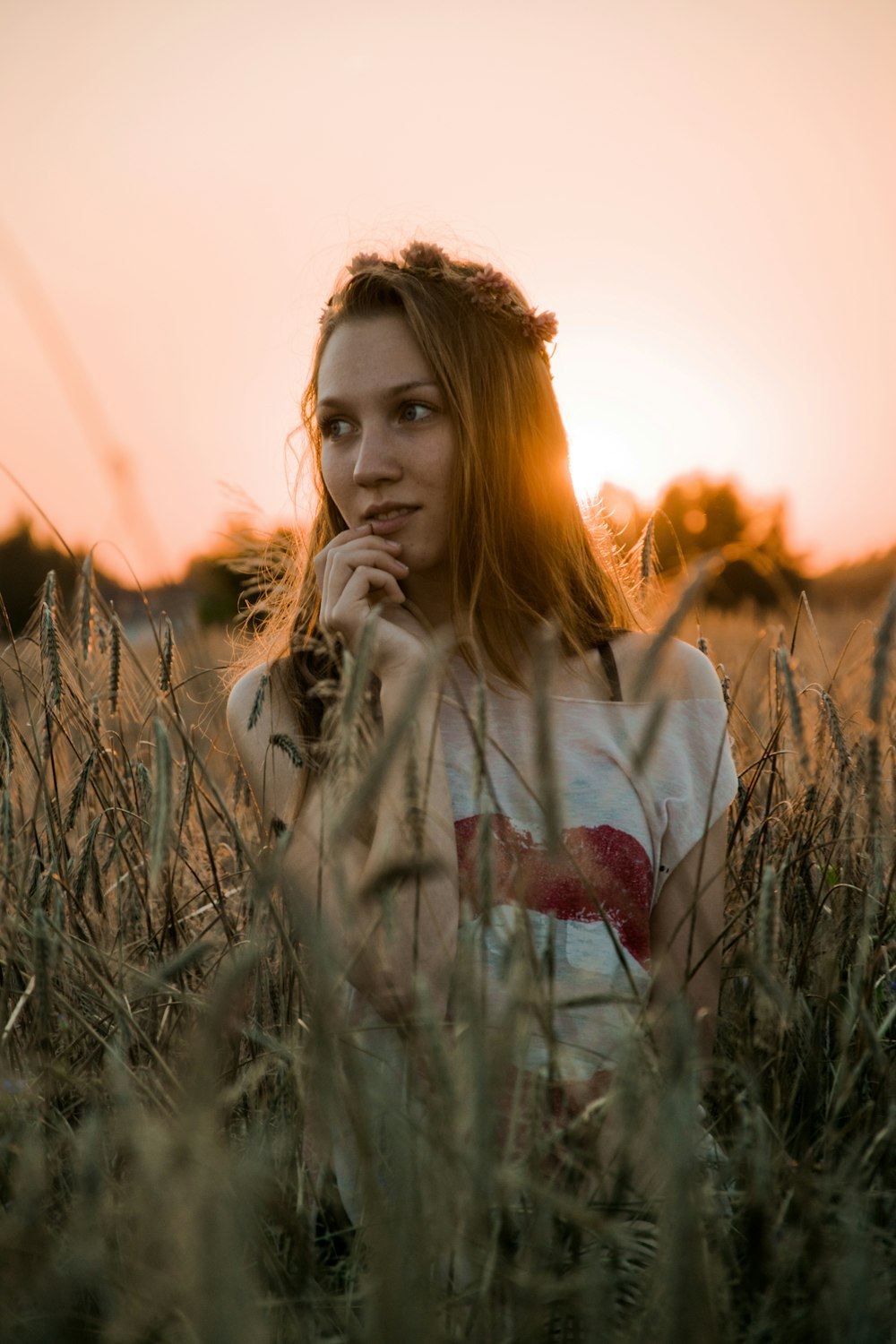 woman in white and red heart printed sweater standing on green grass field during sunset