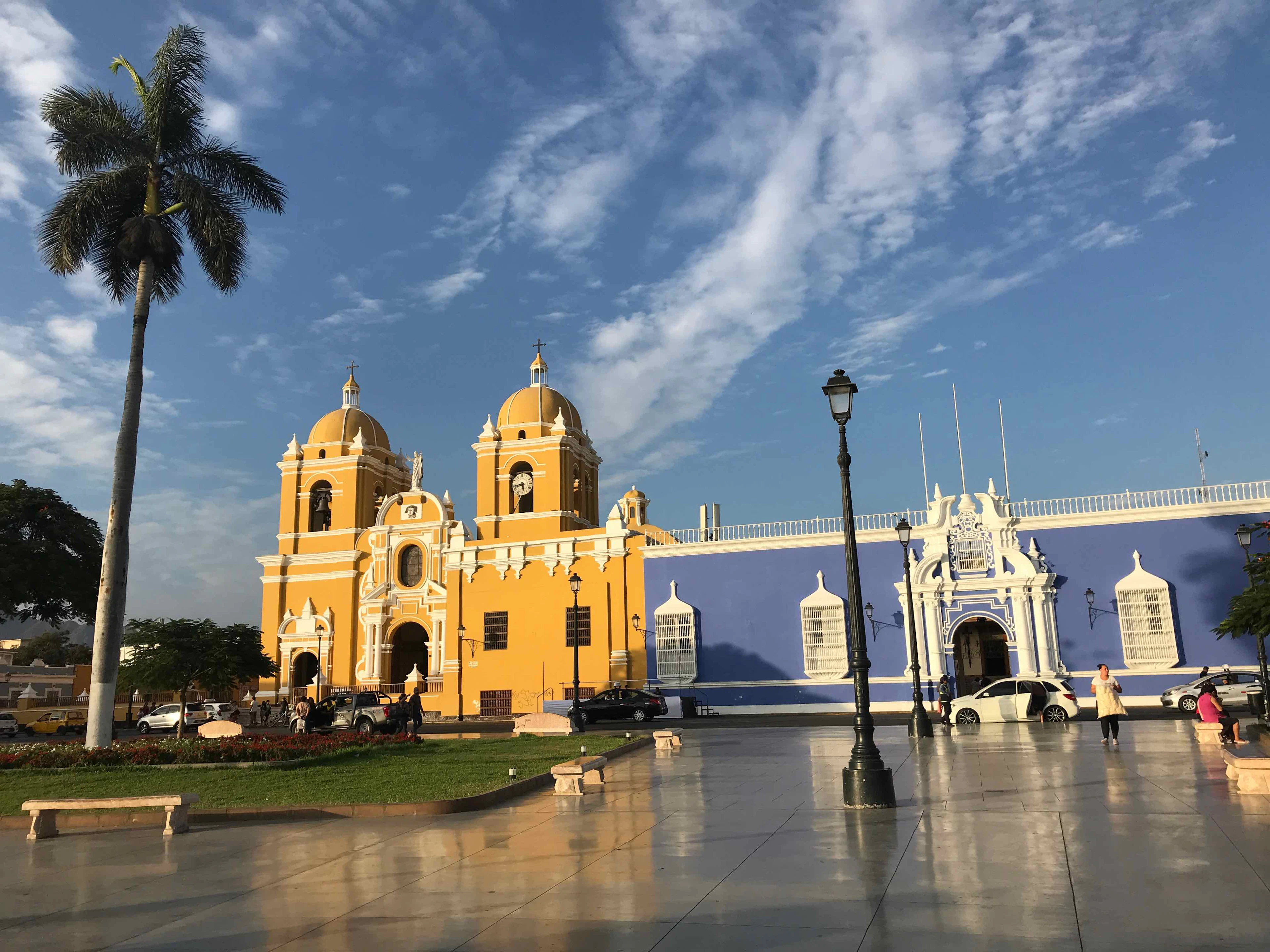 The yellow cathedral and a blue colonial building on the Plaza de Armas in Trujillo