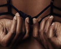 A smiling woman gently adjusting her elegant bra in natural light.