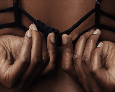 Intimate close-up of hands adjusting leather restraints with a hint of red lighting.