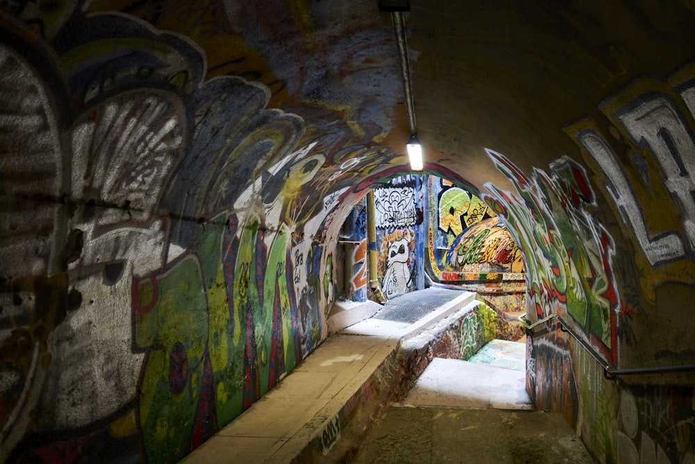 brown wooden bench in front of wall with graffiti