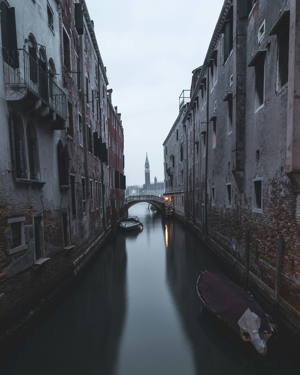 boat on river between concrete buildings during daytime