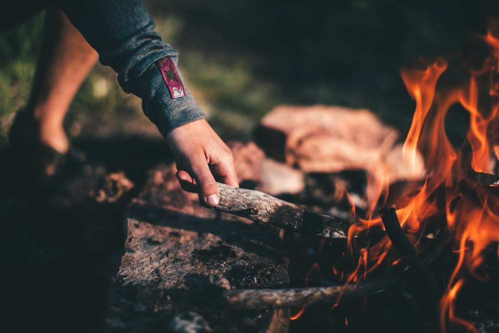 person holding burning wood during daytime