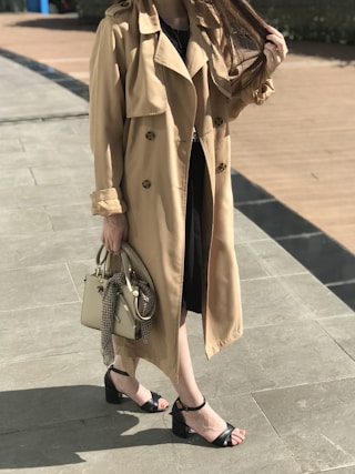woman in brown coat and black leather sling bag