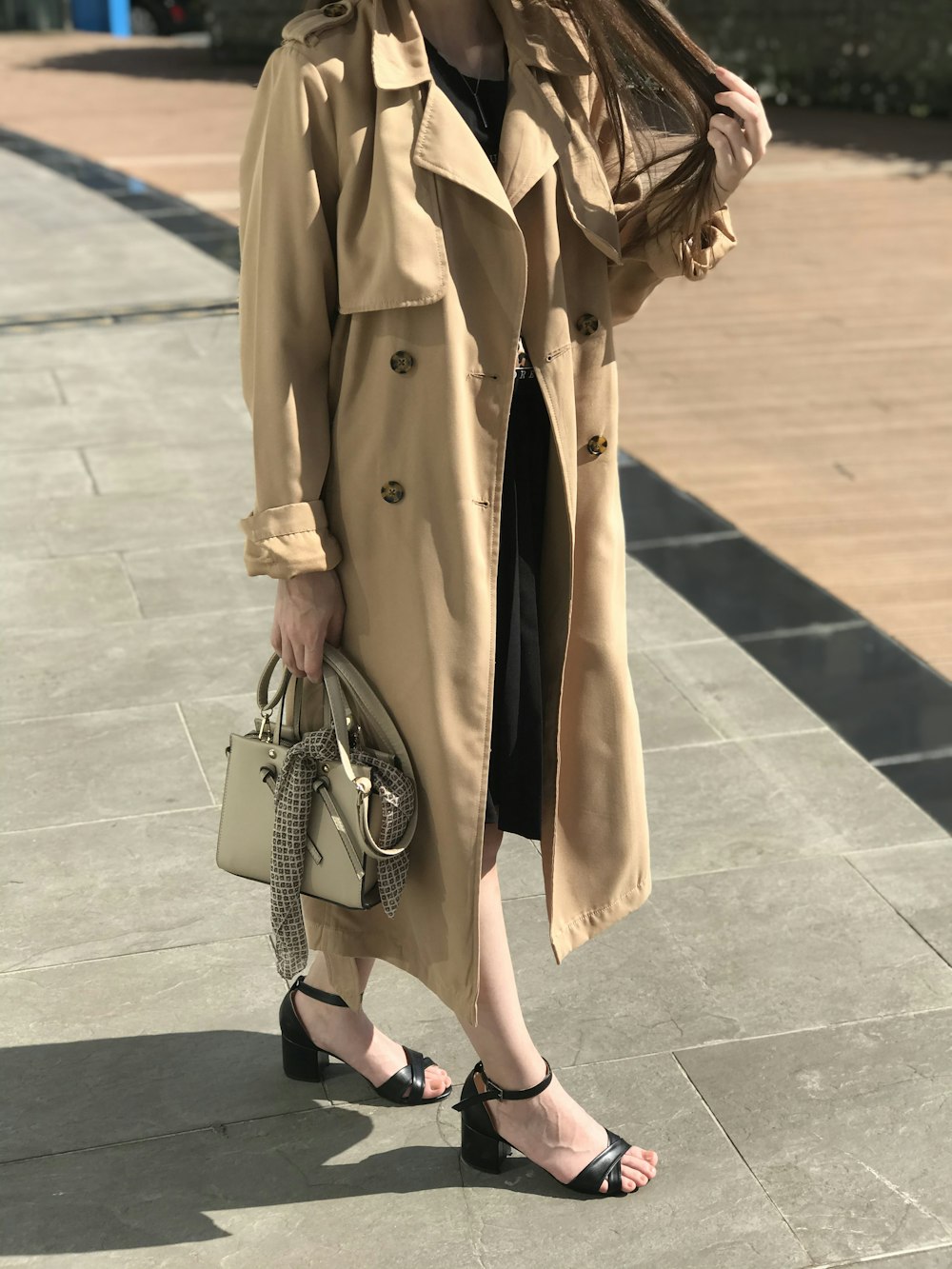 woman in brown coat and black leather sling bag