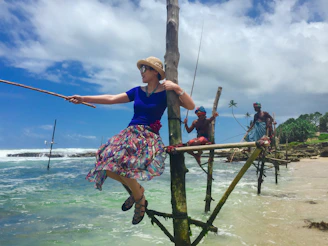 woman in blue and red floral dress sitting on brown wooden ladder during daytime