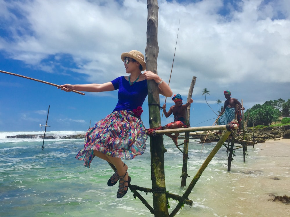 woman in blue and red floral dress sitting on brown wooden ladder during daytime