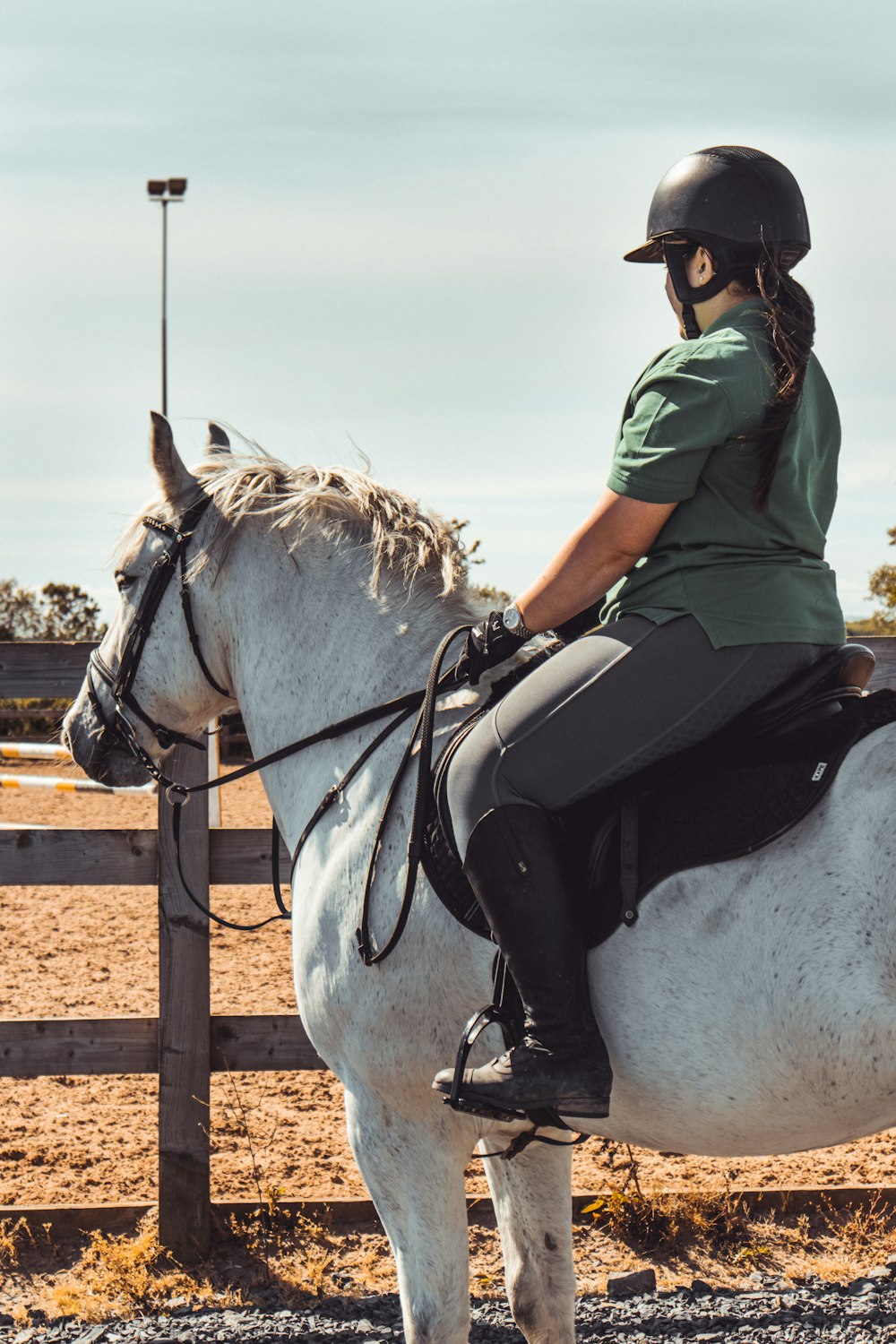 woman in green shirt riding white horse during daytime