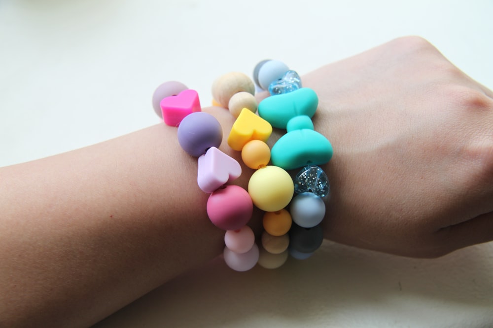 person wearing silver and pink beaded bracelet