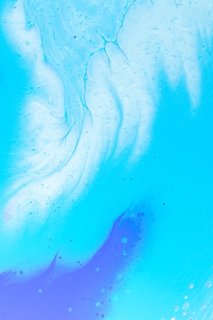 A fluid abstract pattern featuring soft, flowing lines and swirling gradients of blue and white. The design gives the impression of liquid or clouds, with a smooth texture and subtle speckles.