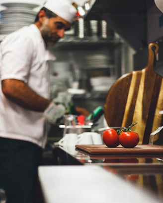 man in white shirt and black pants holding orange tomato