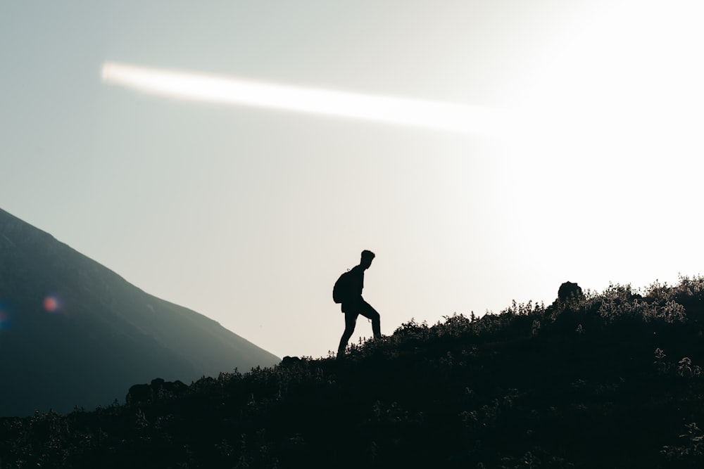 silhouette of man standing on grass field during daytime